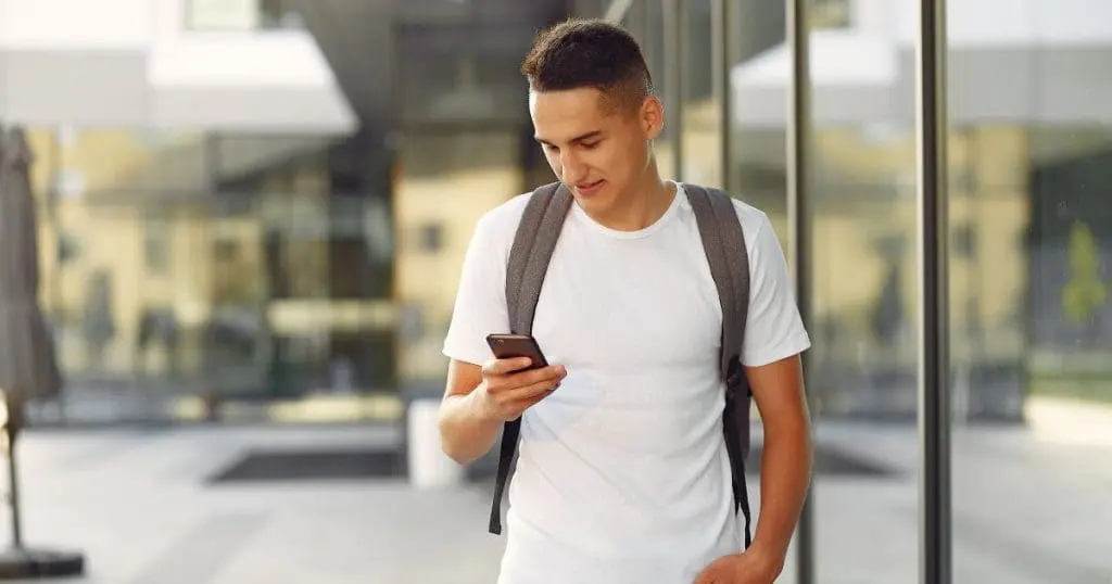 Estudante em um campus universitário com um telefone - O que fazer depois de concluir o ensino médio