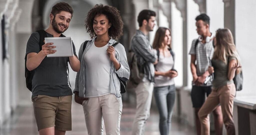 estudantes reunidos olhando para um tablet em ambiente escolar - Conciliar Trabalho e Estudo