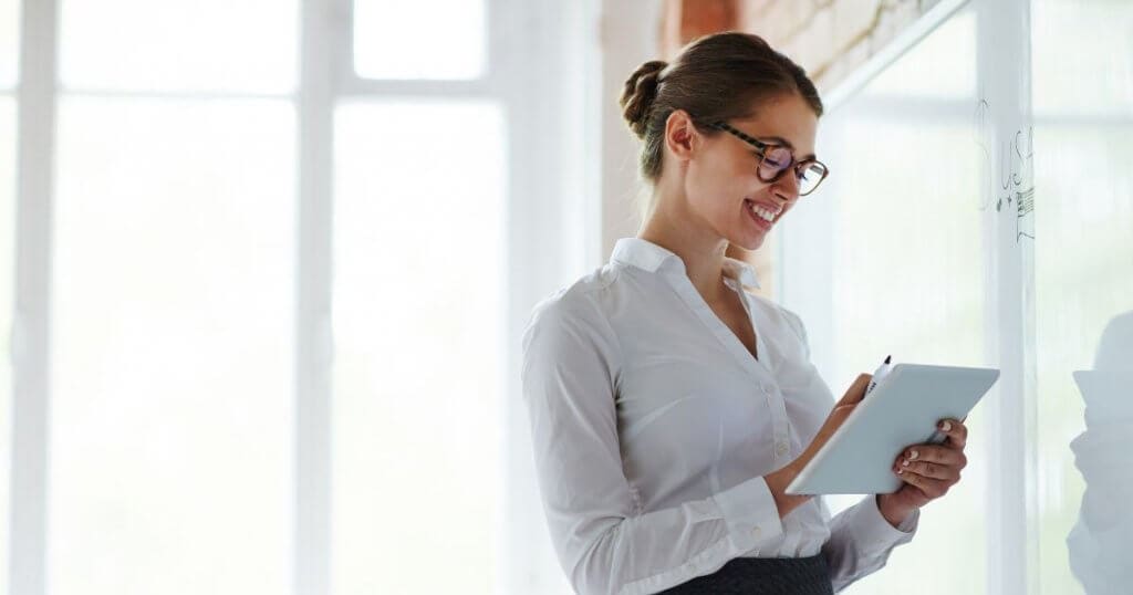 Professora em sala de aula em frente a quadro branco - vantagens de fazer um curso técnico presencial