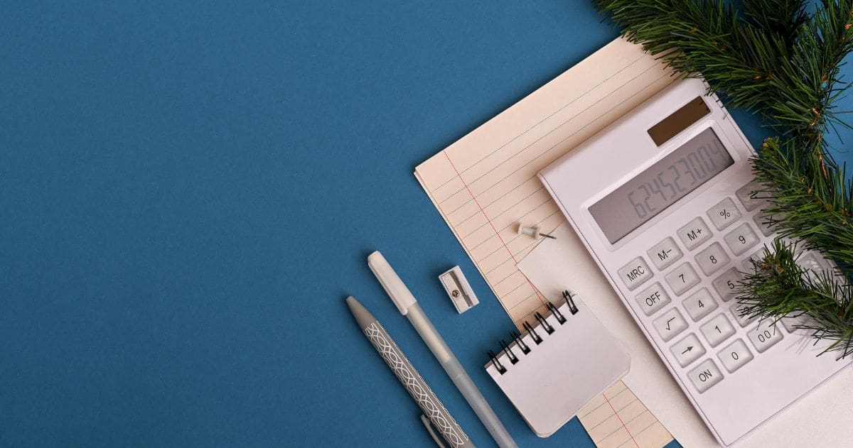 Como se organizar financeiramente para fazer um Curso Técnico? - Vista superior de um caderno, calculadora e demais materiais de escritório em um fundo azul.